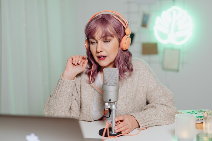 Mujer grabando podcast Podcast: Qué es y cómo puedes crear uno para tu marca, Pasos 2: hora de grabar